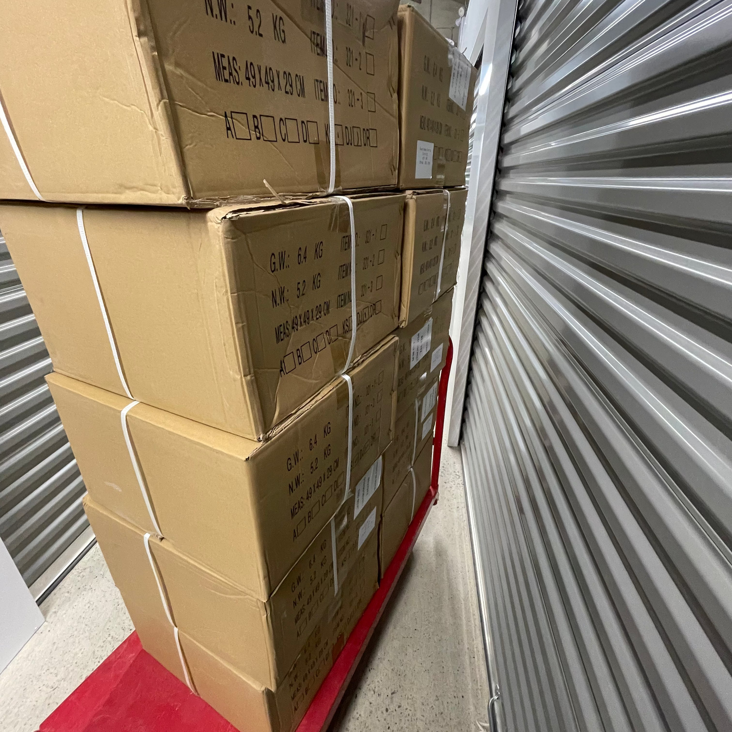 Stack of cardboard boxes in a storage unit with a metal door.