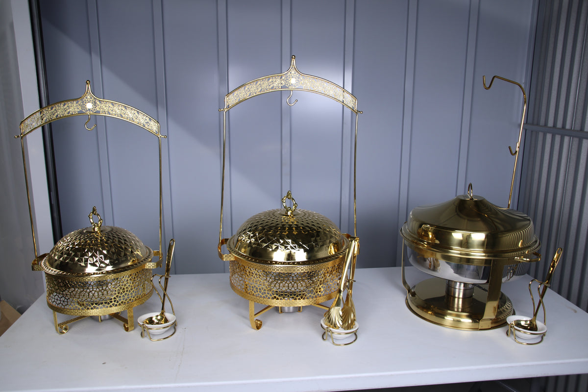 Gold hammered-dome hanging chafing dishes on a table with serving utensils