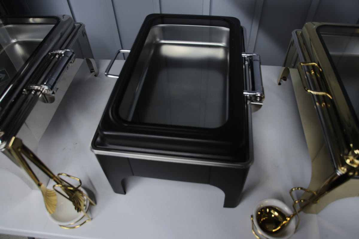 Jet black and gold Crystal Crown rectangle chafing dishes side by side with serving utensils