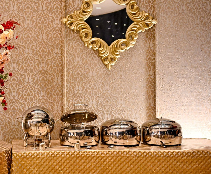 Stock photo: banquet hall buffet with stainless steel chafing dishes on a gold draped table under a gold-framed mirror